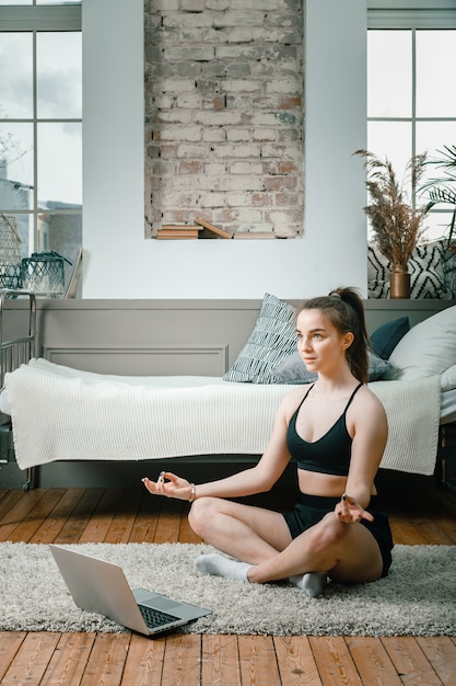 Cheerful sportswoman with blond hair meditates in lotus position