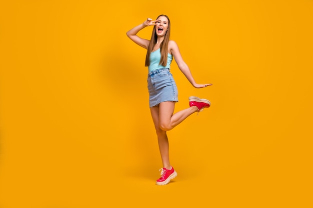  Cheerful straight-haired girl having fun showing v-sign isolated over yellow background