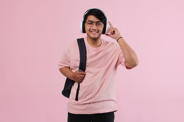 Cheerful student carrying a backpack and listening to music through headphone