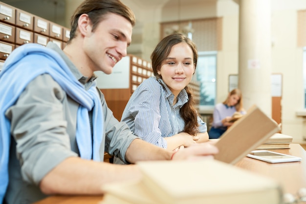 Cheerful students learning new material in library