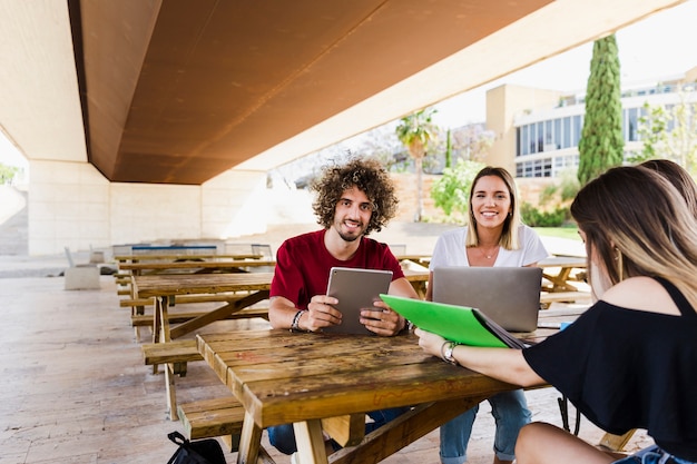 Photo cheerful students with gadgets looking at camera