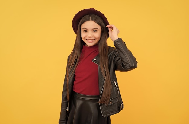 Photo cheerful stylish teen child kid in hat on yellow background autumn season trends