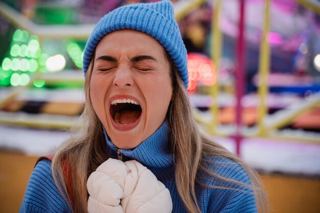 Foto una donna allegra ed elegante vestita con abiti caldi si diverte in un parco divertimenti invernale innevato