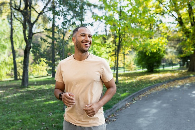 Cheerful and successful hispanic man jogging in the park man running on a sunny day smiling and