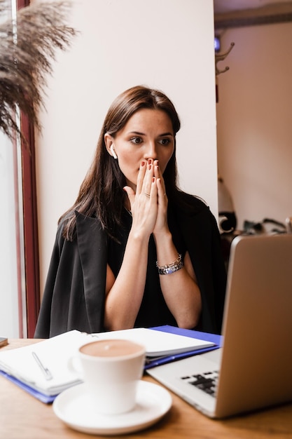 Cheerful surprised woman smile and looking at amount of income earnings in online casino and rejoices Happy girl rejoices in winning bet and sitting in front of laptop in cafe