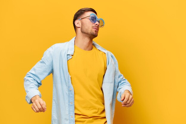 Cheerful tanned handsome man in blue shirt trendy sunglasses\
dance sing posing isolated on orange yellow studio background copy\
space banner mockup relax time party concept