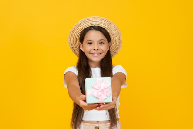 Cheerful teen child hold present box on yellow background