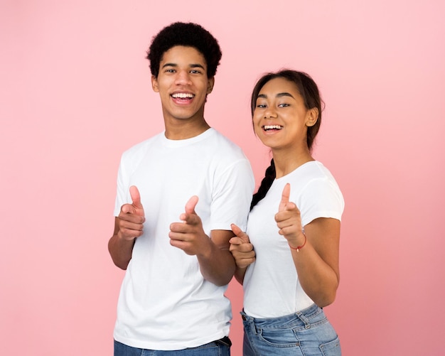 Cheerful teen couple pointing fingers at camera