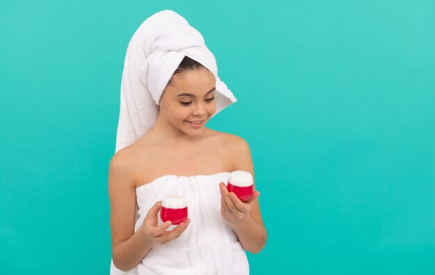 Cheerful teen girl in bath tower presenting body cosmetic skincare