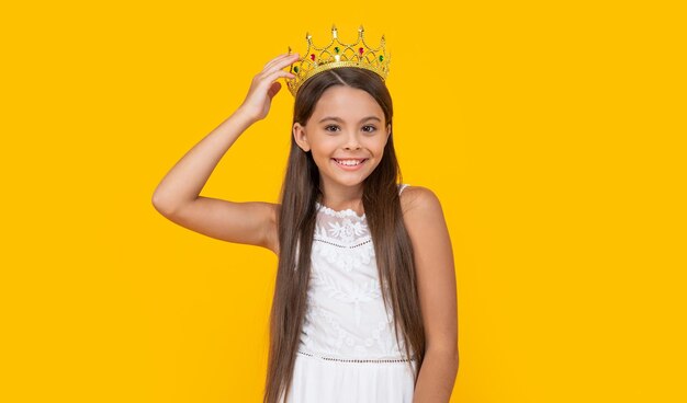 Cheerful teen girl in crown on yellow background