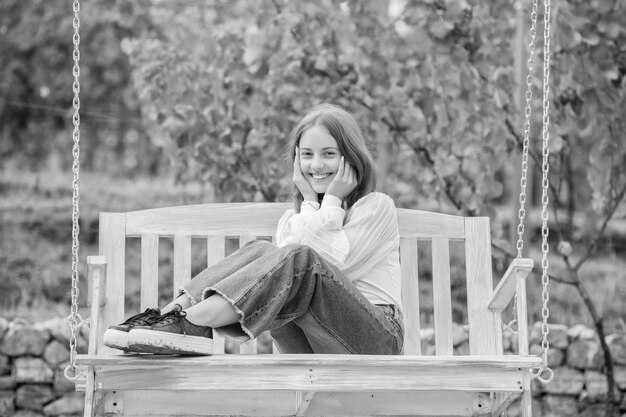 Cheerful teen girl having free time outside on swing relaxation