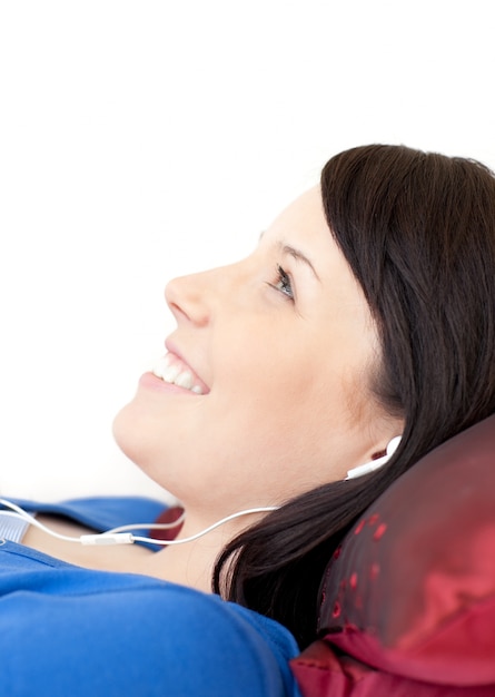 Photo cheerful teen girl listening music lying on a sofa