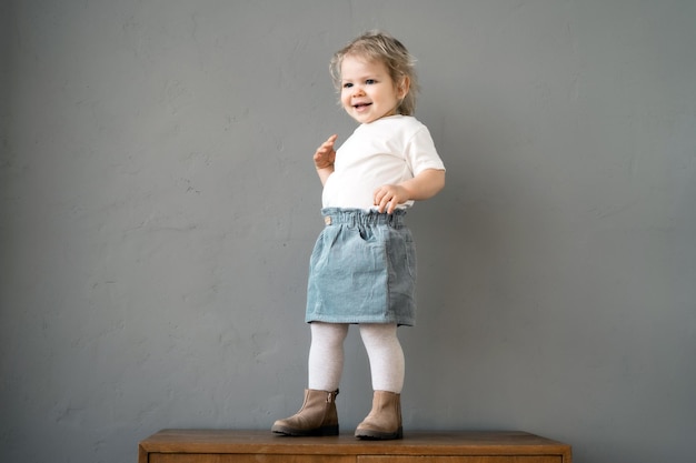 cheerful toddler standing on a bench smiling in a welllit room