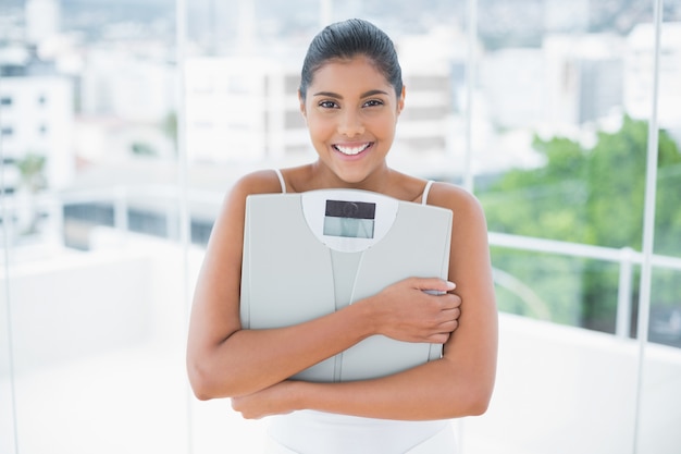 Cheerful toned brunette holding scales