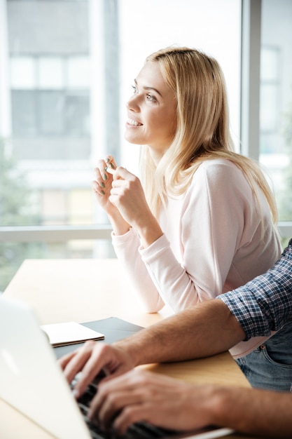 Due colleghi allegri nell'ufficio che coworking mentre per mezzo del computer portatile