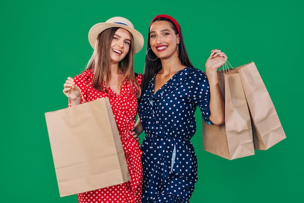 Cheerful two young women friends in dresses isolated on a green