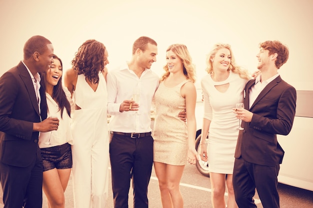 Cheerful well dressed people standing next to limousine on night out