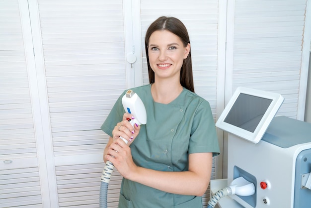 Cheerful woman adjusts laser hair removal machine She holds working part