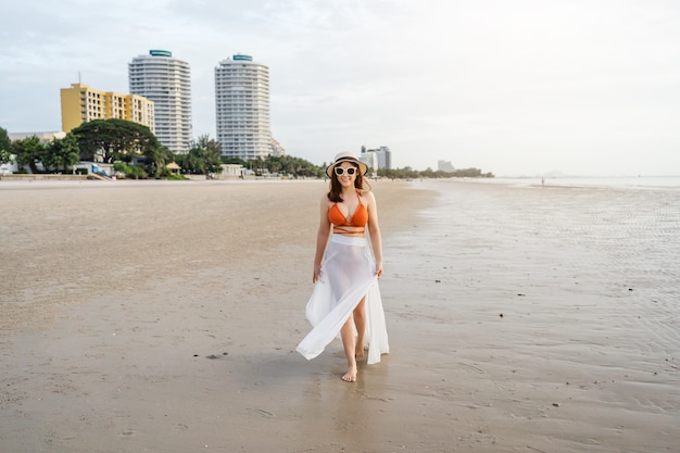 海のビーチを歩くビキニの陽気な女性