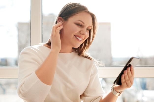 Cheerful woman browsing playlist on smartphone