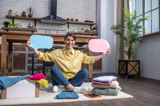 Cheerful woman calling for donating unwanted items of clothing