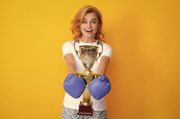 Cheerful woman celebrating victory Woman in boxing gloves hold champion winner cup trophy Winner