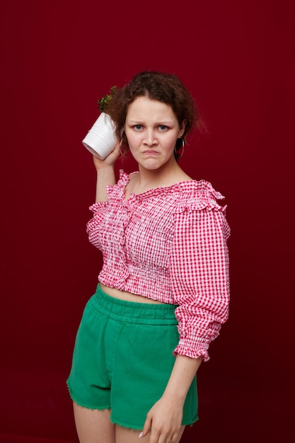 Cheerful woman in colorful clothes flowerpot red background unaltered