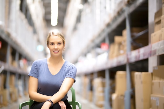 Cheerful woman customer looking at camera and sitting on chair while shopping in hardware store