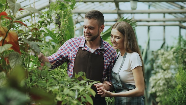 陽気な女性は植木鉢で花に水をまく彼女の夫を抱きしめます