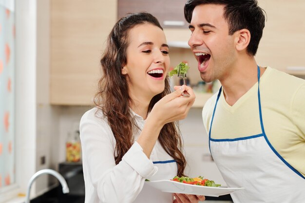 Cheerful woman feeding husband