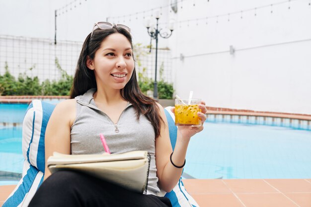 Cheerful woman filling journal