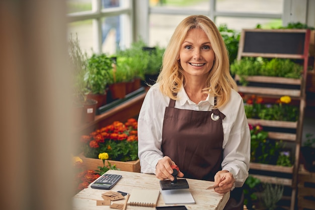 Cheerful woman florist sitting at a desk