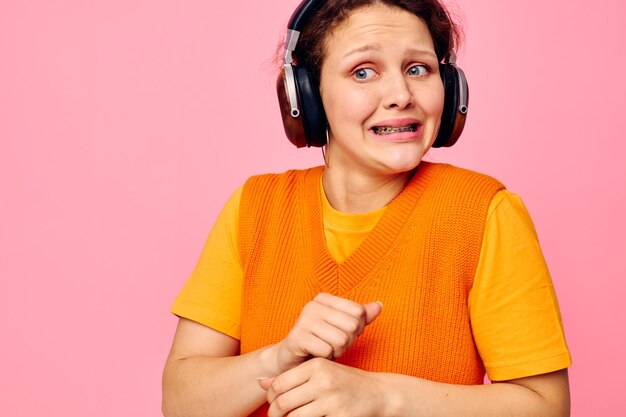 Cheerful woman grimace headphones entertainment emotions music pink background unaltered. high quality photo