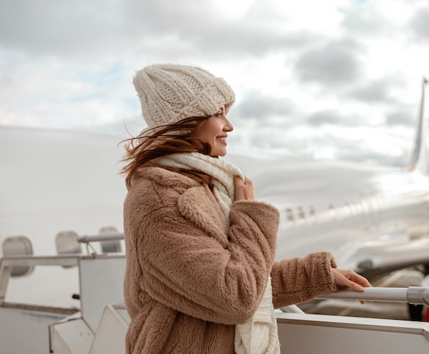 Cheerful woman in hat standing outdoors at airport