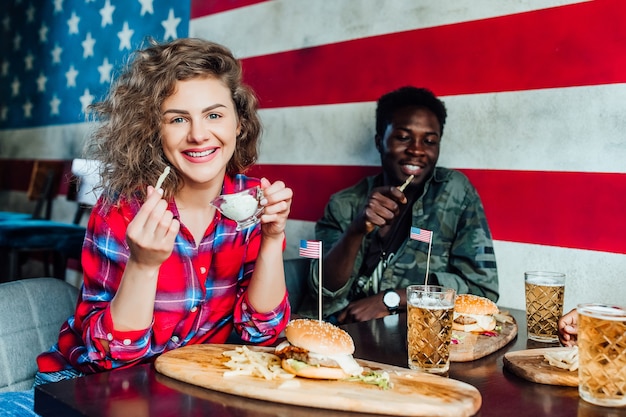 Cheerful woman having a resting in bar with man at cafe, talking, laughing eat fast food.