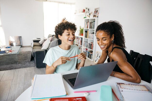 Photo cheerful woman helping her smiling daughter doing homework happy mother assisting her daughter with school homework in living room