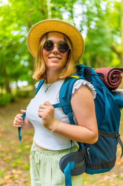 Cheerful woman hiking on forest path with backpack