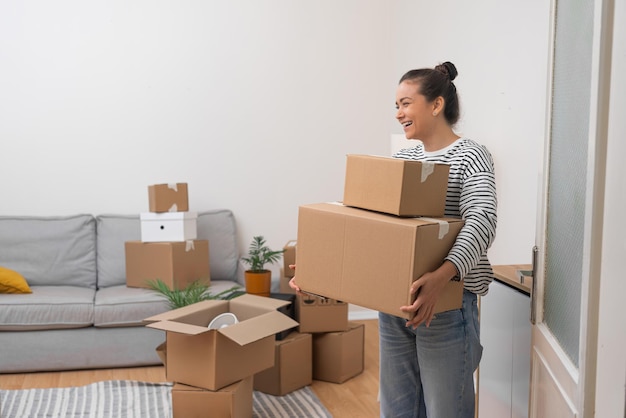 Cheerful woman holds packed boxes with household goods