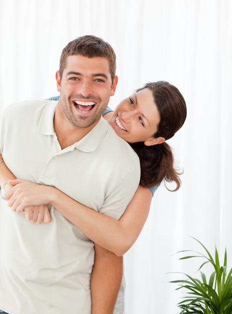 Photo cheerful woman hugging her husband standing in the living room