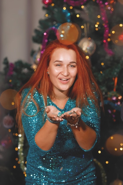 Cheerful woman is dancing near the Christmas tree. Women laugh, rejoice.