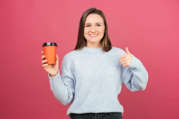 テイクアウトカップを持って元気な女性がジェスチャーのように見せている