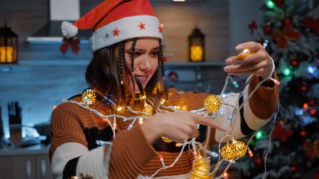 Cheerful woman laughing at tangled rope with lights