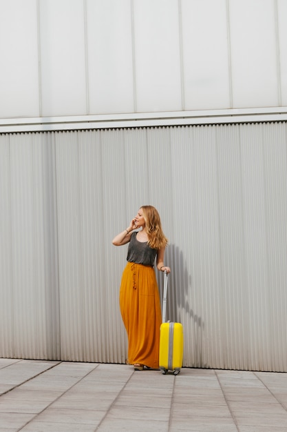 Cheerful woman looking for her destination with her suitcase