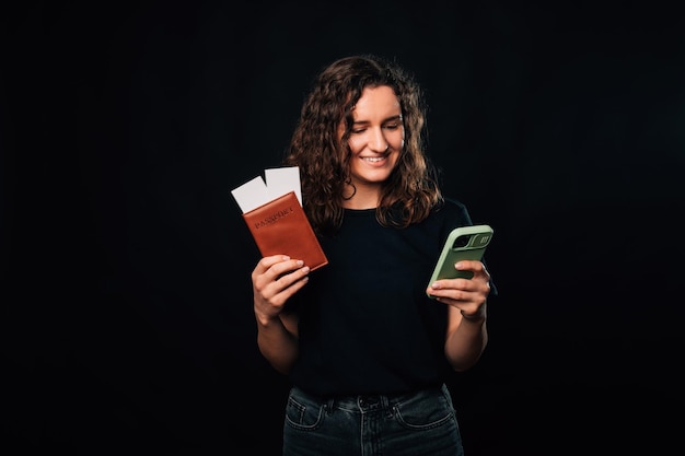 Cheerful woman makes check in online over the phone while holding her passport