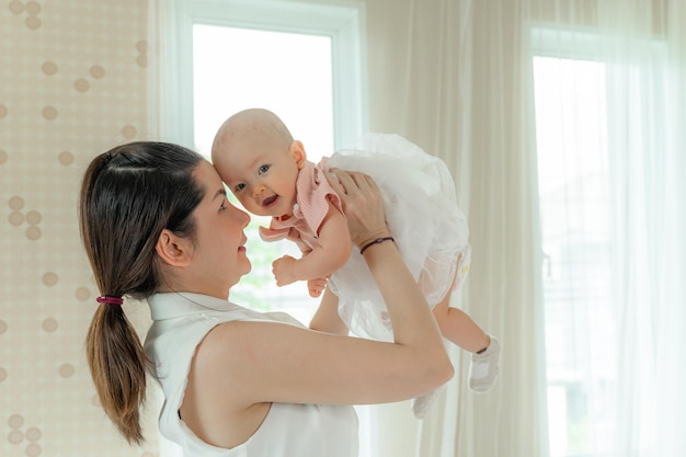 Cheerful woman playing with adorable infant child