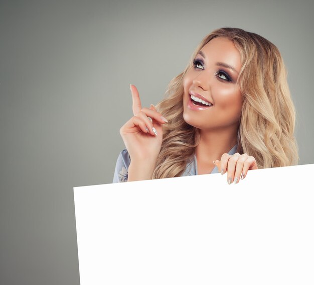 Photo cheerful woman pointing her finger and holding white paper banner background