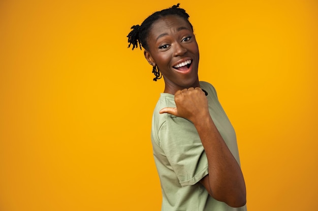 Cheerful woman points to copy space in yellow studio