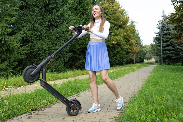 Cheerful woman puts her electric scooter on one wheel