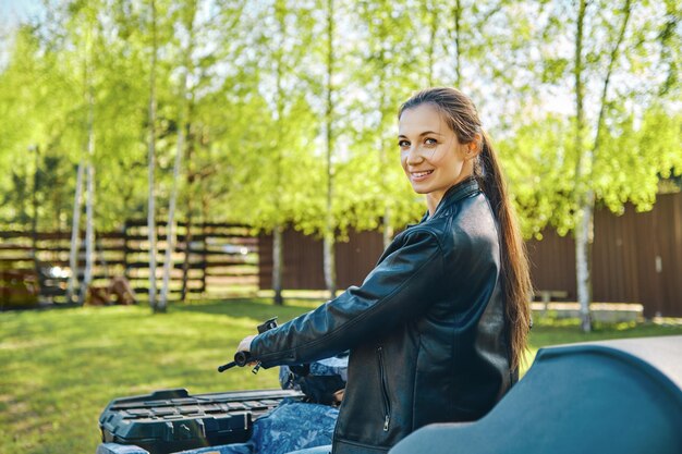 Cheerful woman on quad bike looking back before ride