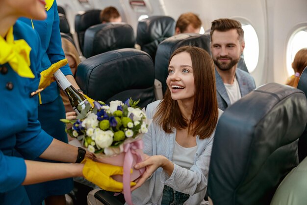 Cheerful woman receiving gifts from stewardesses in airplane